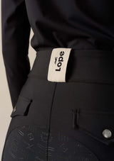 ridklädd kvinna med svarta funktions ridbyxor med kompression bakifrån