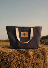 lope tote, stallväska med inner fack och dragkedja i gråsvart på en höbal. perfekt tote bag för ridning, jobb och träning.