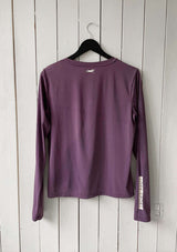 En lila långärmad tröja i ett mjukt, silkesliknande material. Tröjan har rund halsringning och ett upphöjt häst 3D-tryck i silikon i nacken samt "LOPE SPORT" tryckt längs ena ärmen.