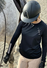 En svart långärmad tröja i ett mjukt, silkesliknande material. Tröjan har rund halsringning och ett upphöjt 3D-tryck i silikon med texten "LOPE" snett över bröstet samt "LOPE SPORT" tryckt längs ena ärmen.