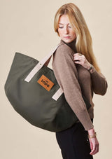 Lope Tote Bag Gröngrå stallväska. Tyg: 900D polyester i grågrön färg. Axelband: Vävda band i crèmevitt med nedsänkt text LOPE SPORT. Sömmar: SPI (stitches per inch): 8–9. Foder: Dubbelt tyg (samma polyester även som insida). Tråd: Nylon, med hög slitstyrka. Logo-lapp: Cognacsfärgat PU-läder med svart nedsänkt präglad logotyp. Stängningsrem: Cognacsfärgat PU-läder med tryckknapp i antik mässing präglad med logotyp