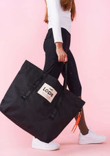 Svart snygg rymlig väska i trendig design. På väskan hänger en färgglad bag charm