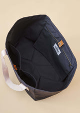 uppifrån vy av lope tote bag, stallväska Tyg:&nbsp;900D polyester i gråsvart färg. Axelband: Vävda band i crèmevitt med nedsänkt text LOPE SPORT. Foder: Dubbelt tyg (samma polyester även som insida). Logo-lapp: Cognacsfärgat PU-läder med svart nedsänkt präglad logotype. Stängningsrem: Cognacsfärgat PU-läder med&nbsp; tryckknapp i antik mässing präglad med logotype.