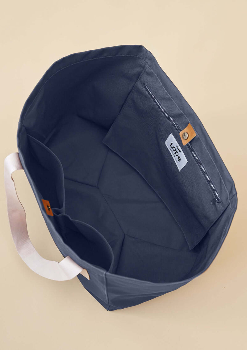 lope tote bag, stallväska Tyg 900D polyester i gråblå färg. Axelband: Vävda band i crèmevitt med nedsänkt text LOPE SPORT. Foder: Dubbelt tyg (samma polyester även som insida). Logo-lapp: Cognacsfärgat PU-läder med svart nedsänkt präglad logotype. Stängningsrem: Cognacsfärgat PU-läder med&nbsp; tryckknapp i antik mässing präglad med logotype.