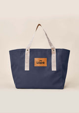 Lope Tote  midnattsblå– din nya favoritväska till stallet, jobbet och träningen. Tyg: 900D polyester i blåsvart färg. Axelband: Vävda band i crèmevitt med nedsänkt text LOPE SPORT med en nit i antik mässing Foder: Dubbelt tyg (samma polyester även som insida). Tråd: Nylon, med hög slitstyrka. Logo-lapp: Cognacsfärgat PU-läder med svart nedsänkt präglad logotyp.
