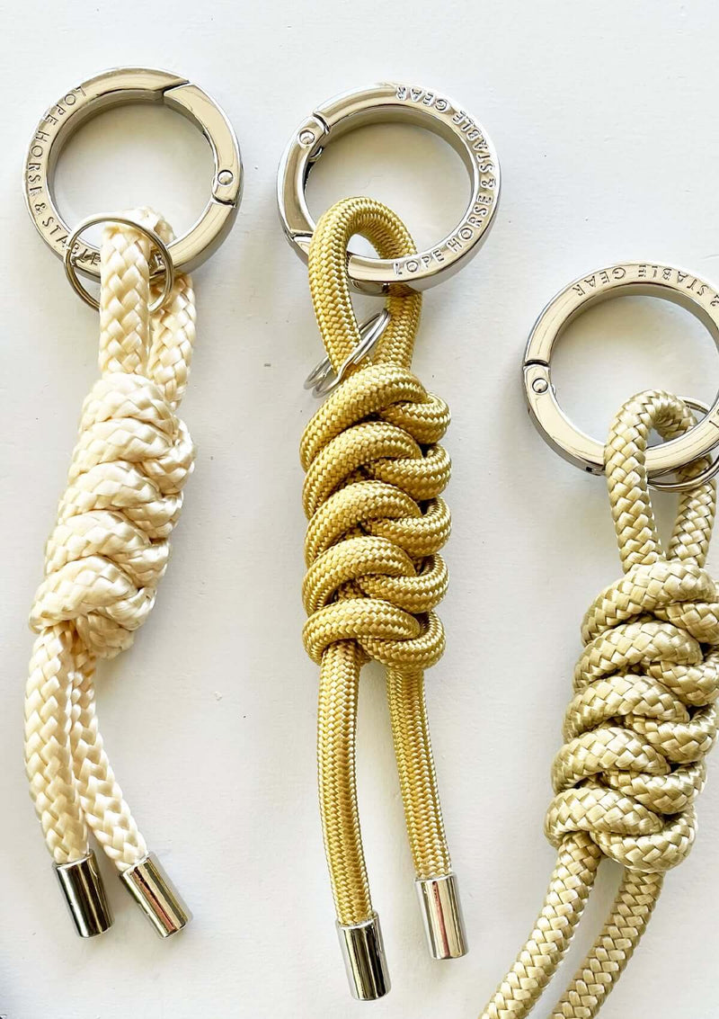 Snygga nyckelringar, bag charms i para cord i guldiga nyanser och cromad logo präglad rund ring