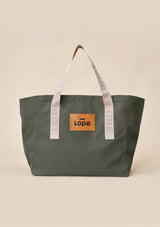 Lope Tote Bag Gröngrå stallväska. Tyg: 900D polyester i grågrön färg. Axelband: Vävda band i crèmevitt med nedsänkt text LOPE SPORT. Sömmar: SPI (stitches per inch): 8–9. Foder: Dubbelt tyg (samma polyester även som insida). Tråd: Nylon, med hög slitstyrka. Logo-lapp: Cognacsfärgat PU-läder med svart nedsänkt präglad logotyp. Stängningsrem: Cognacsfärgat PU-läder med tryckknapp i antik mässing präglad med logotyp