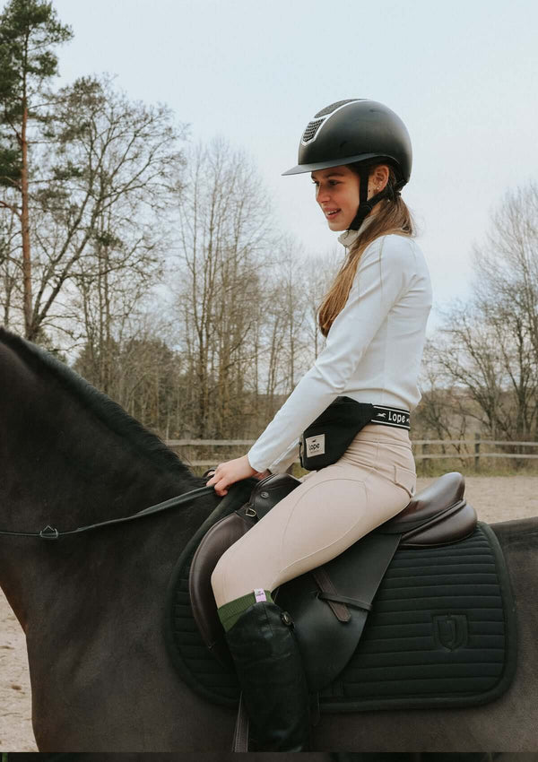 Vår PERFORMANCE TOP JUNIOR, WHITE är en krispigt vit, långärmad ridtopp i fyrvägsstretch med high-tech funktionsmaterial. Perfekt för träning med en något tjockare kvalitet och högre hals. Stilren metallblixtlås med skyddande söm förhindrar friktion mot hakan. Toppen är liten i storlek, motsvarande en Small. Modellerna Stephanie (164 cm, storlek M) och Polly (156 cm, storlek S) visar hur den sitter. Kombinera med The Competition socks i Black + White diamond för en matchande look