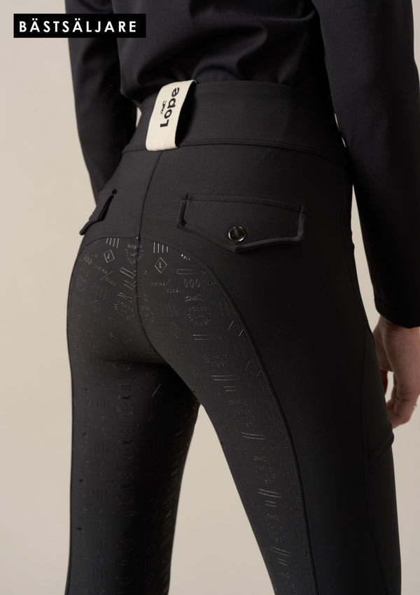 best seller-svarta Bekväma ridbyxor med hög midja och skulpterande passform. Tillverkade i fyrvägsstretch för optimal rörelsefrihet, med en mobilficka med lock och broderad häst. Helskodda med grip för rätt friktion i sadeln. True to size och med en Stay-in-place garanti som säkerställer att byxorna sitter uppe oavsett kroppsform