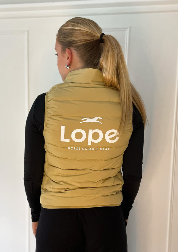 Gul ridväst i dun för kvinnor i matt finish. Vitt tryck på ryggen "Lope Horse  and stable Gear" Brodyr på vänster front. Kanter med elastiskt band i ärm och midja.