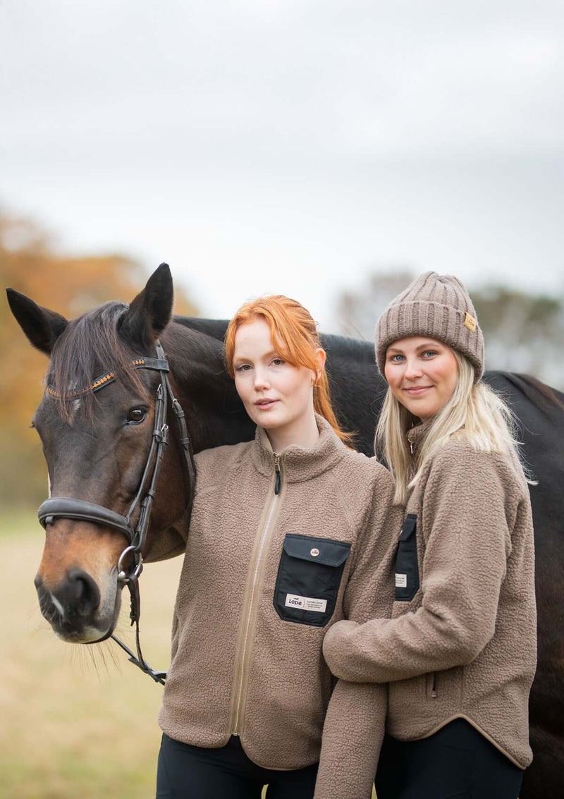 mjuk och vindtät stall fleece för ryttare. detaler  och dragkedja i light gold och svart mobilficka på böstet. Kvinnlig passform med rundat avslut