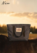 grå stallväska i tote bag stil med plast coatad insida. smuts och vatten resistent plats för all stallutrustning står på en hästrygg