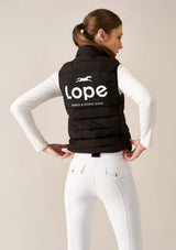 Svart ryttarväst, vit lope logotyp på ryggen på ridklädd tjej 