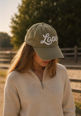 grön keps med vintage inspirerad lope logo i filt på fronten och broderad häst på sidan