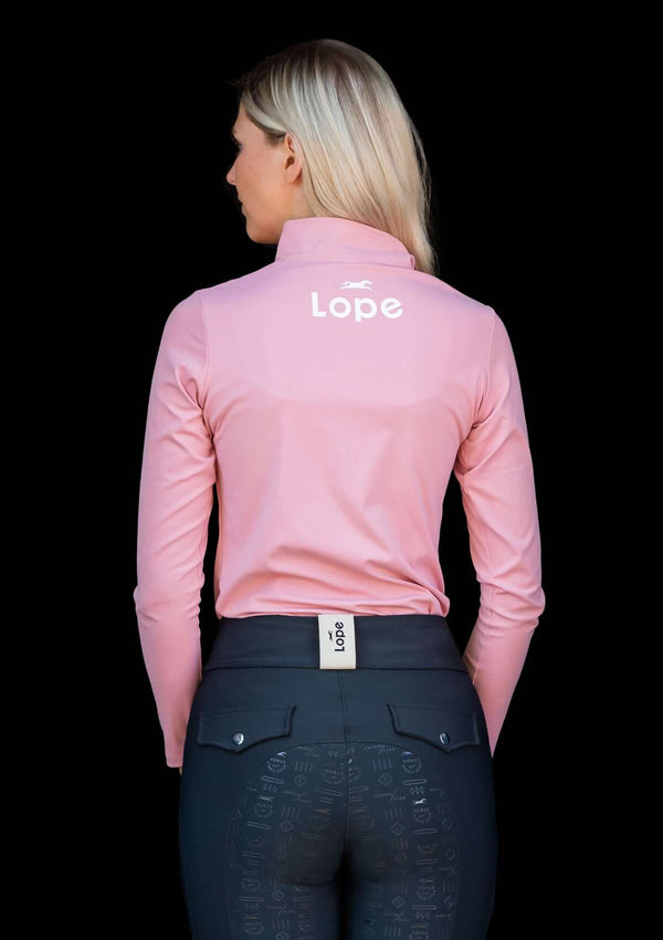 Pink blush, rosa Sport topp i klassisk quarter Zip modell. Halvpolo krage med en dragkedja i matchande färg av metall. Super stretchigt funktionsmaterial som andas. Figurnära passform. Toppen har tryck på vänster ärm samt på ryggen i vitt. Mjuk och följsa