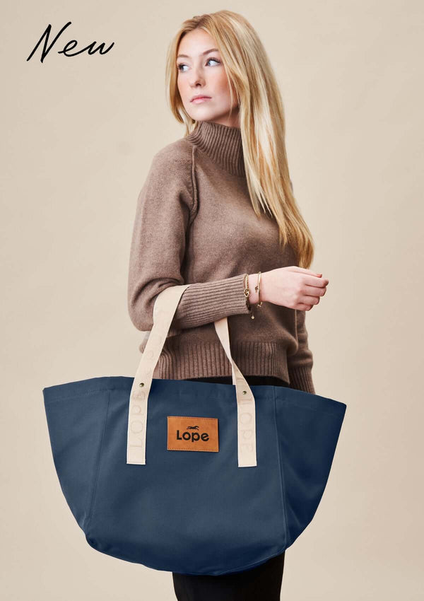 Lope Tote  midnattsblå– din nya favoritväska till stallet, jobbet och träningen. Tyg: 900D polyester i blåsvart färg. Axelband: Vävda band i crèmevitt med nedsänkt text LOPE SPORT med en nit i antik mässing Foder: Dubbelt tyg (samma polyester även som insida). Tråd: Nylon, med hög slitstyrka. Logo-lapp: Cognacsfärgat PU-läder med svart nedsänkt präglad logotyp.