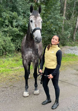 En gul dunväst för ridning med horisontella quiltade sömmar. Västen har hög krage och stort vitt tryck på ryggen med texten "Lope Horse & Stable Gear" samt en springande hästsilhuett ovanför loggan samt broderad logo vid vänster bröst

