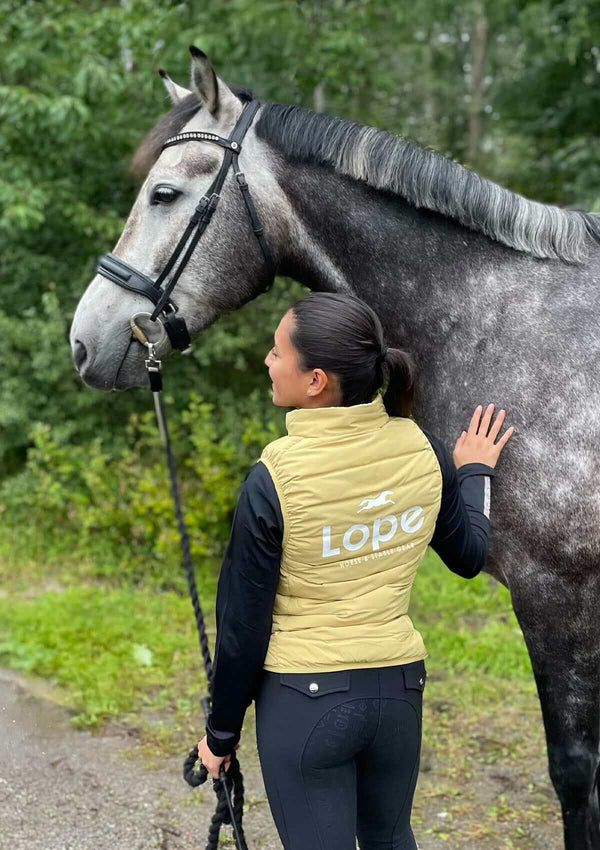 En gul dunväst för ridning med horisontella quiltade sömmar. Västen har hög krage och stort vitt tryck på ryggen med texten "Lope Horse & Stable Gear" samt en springande hästsilhuett ovanför loggan