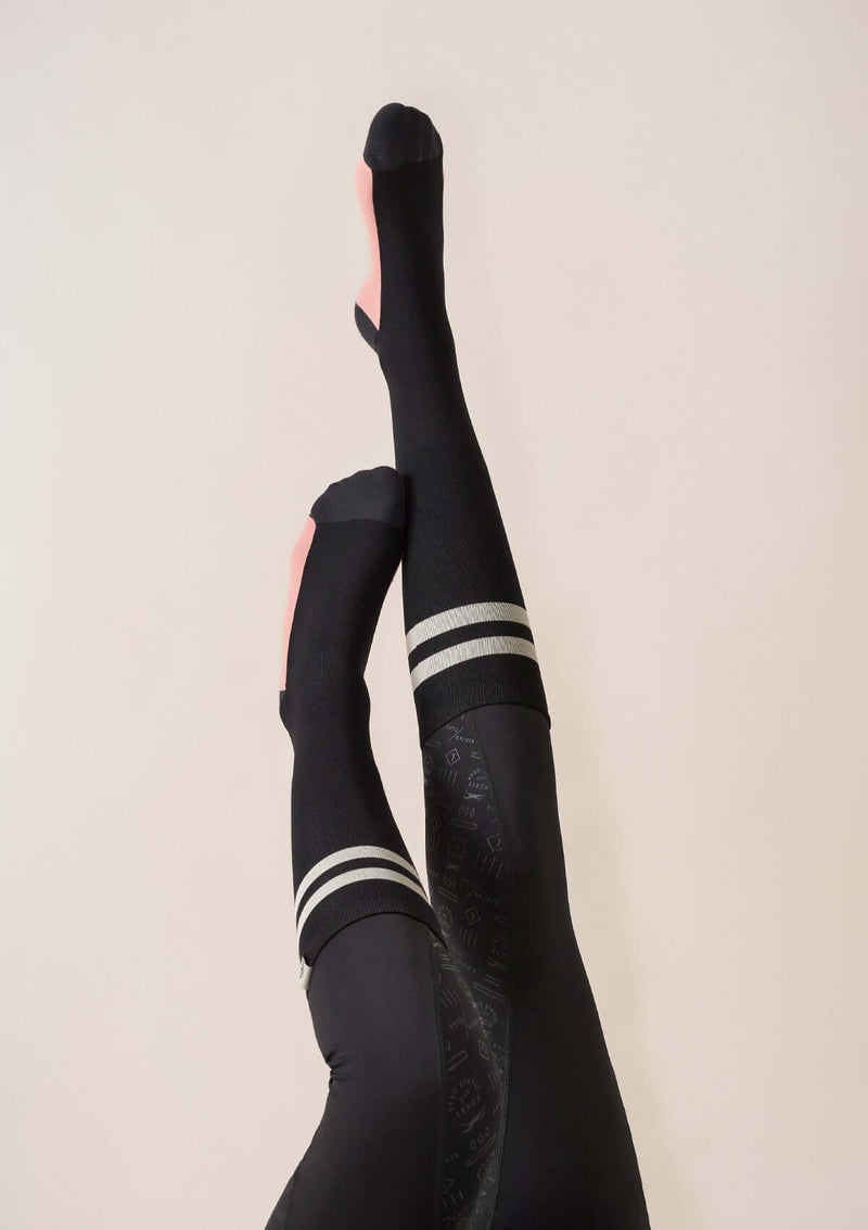 snygga svarta ridstrumpor med grafiska sportiga ränder, rosa på foten i en lekfull detalj. hållbart material