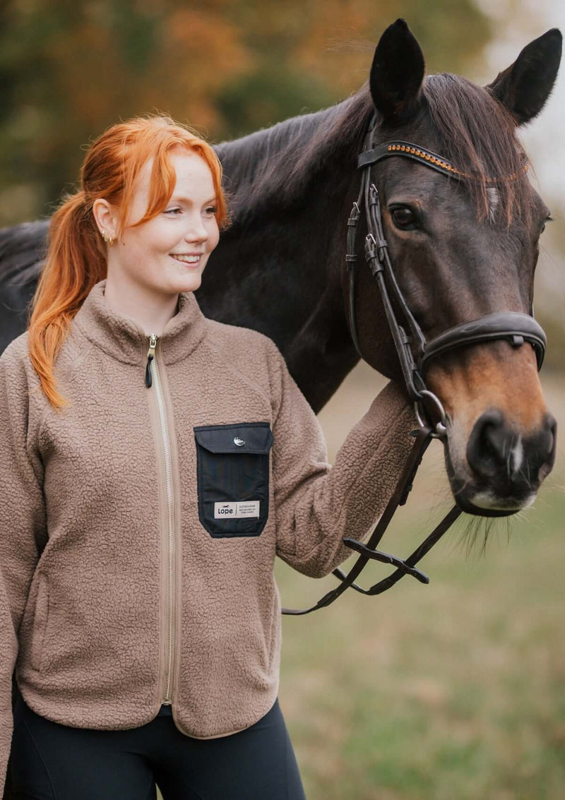 stable fleece i varm beige med svart ficka och detaljer i light gold. mjuk teddy med vindtött fodet kvinlig passform