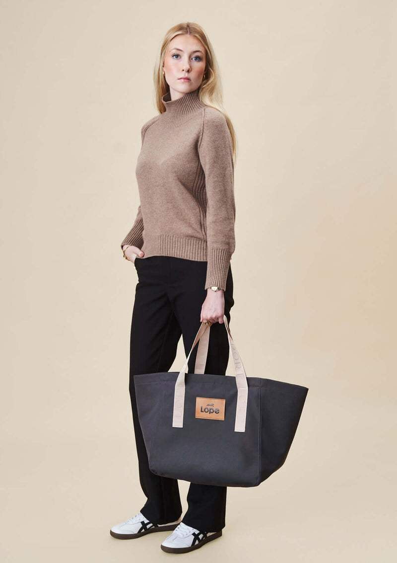 lope tote bag, stallväska Tyg:&nbsp;900D polyester i gråsvart färg. Axelband: Vävda band i crèmevitt med nedsänkt text LOPE SPORT. Foder: Dubbelt tyg (samma polyester även som insida).  Logo-lapp: Cognacsfärgat PU-läder med svart nedsänkt präglad logotype. Stängningsrem: Cognacsfärgat PU-läder med&nbsp; tryckknapp i antik mässing präglad med logotype.