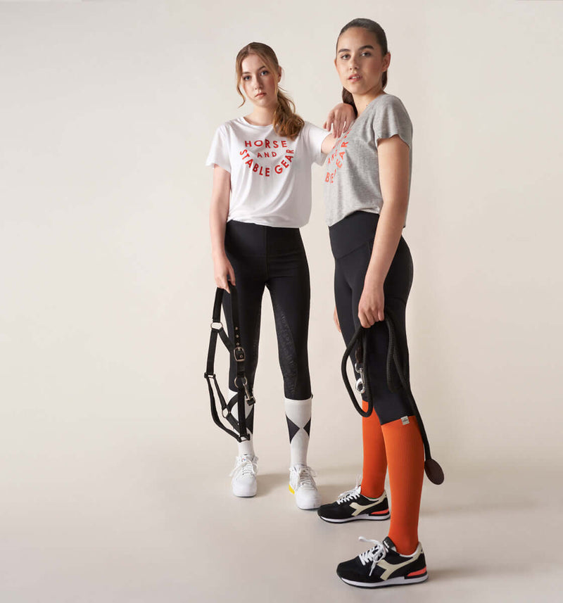 firm compression riding socks, stretchy and durable blend of polyamide and elastane. orange.firm compression riding socks, stretchy and durable blend of polyamide and elastane. orange. long compression comfortable sporty stylish riding socks. with lope logo. girls wearing competition socks, the core riding tights leggings and the stable t-shirt