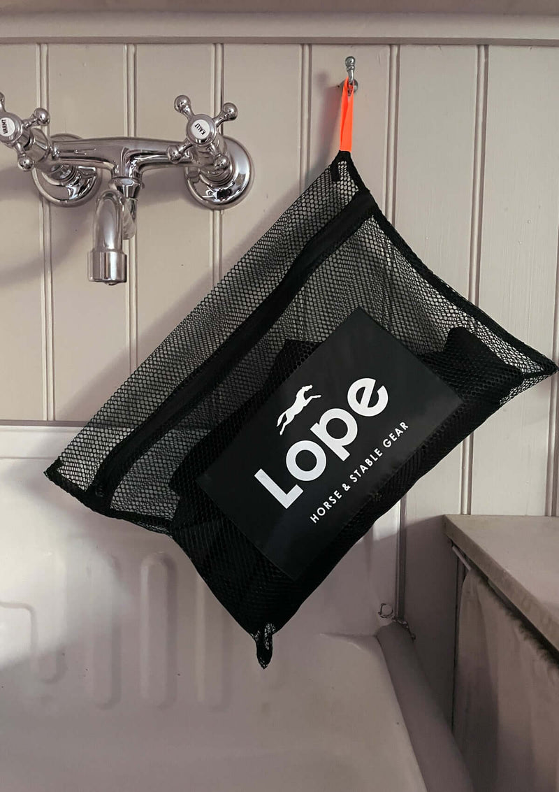 en svart tvättpåse i mesh material med en påsydd etikett med screen tryckt lope logotype
