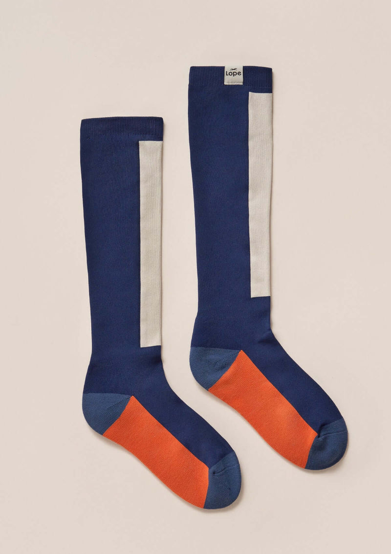 light compression riding socks, stretchy and durable blend of polyamide and elastane. blue sock with white and a pink square  knee high long comfortable durable high quality performance enhancing sport sockslight compression riding socks, stretchy and durable blend of polyamide and elastane. black sock with pink and off white  square knee high long comfortable durable high quality performance enhancing sport socks knähöga kompressions ridstrumpor i snygg hållbar design blå orange vita